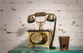 Golden antique telephone set and pottery mug on green vintage wooden table and white bricks wall Royalty Free Stock Photo