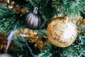 A golden ball hangs on an artificial Christmas tree decorated with a gold garland Royalty Free Stock Photo