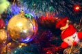 Golden ball and knitted toy hang on a green Christmas tree Royalty Free Stock Photo