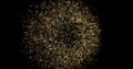 A golden ball of shiny and shimmering particles disintegrates on a black background.