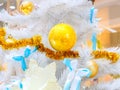 Golden balls and tinsel and white-blue bows on the branches of a white Christmas tree Royalty Free Stock Photo