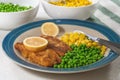 Golden batter deep fried fish fillet, served with green peas, sweet corn, and slices of lemon close up Royalty Free Stock Photo