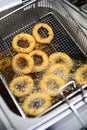 Golden battered onion rings frying in hot oil