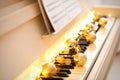 Golden baubles and fairy lights on piano keys, closeup. Christmas music Royalty Free Stock Photo