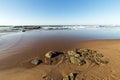 Golden Beach Sand Rocks and Reflections Against Blue Skyline Royalty Free Stock Photo