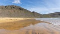 Golden beach of the Westfjords with reddish sand, green meadows in the foreground and shallow, hazy hills in the