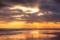 Golden beams of sunlight God rays breaking through dark stormy clouds over a beach Royalty Free Stock Photo