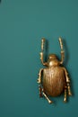 A golden beetle against a green wall. Interior design.Decoration of the walls.