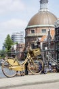 Golden bike with basket with some building in Amsterdam