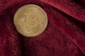 Golden bitcoin coin on a burgundy red velvet background