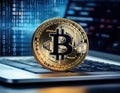 Golden Bitcoin coin placed on a sleek silver laptop keyboard, with glowing binary code streaming across the screen in the Royalty Free Stock Photo