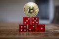 Golden Bitcoin coin stands on a stack of red dice Royalty Free Stock Photo
