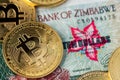 Golden Bitcoin coins new virtual money on Zimbabwe hyperinflation banknote close up image.