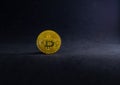 Golden Bitcoin on the floor with black background. Gold digital coin on black with light and shadow