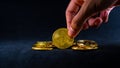 Golden bitcoin, Hand picked bitcoin at a middle of pile, Black background with ray of light