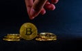 Golden bitcoin, Hand is about to picked bitcoin at a middle of pile, Background with ray of light