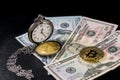 Golden bitcoin lying on us dollars with pocket watch on black Royalty Free Stock Photo