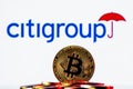 Golden bitcoin in a pile of coins on the background of Citigroup logo