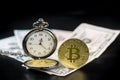 Golden bitcoin and pocket watch on us dollars standing on dark Royalty Free Stock Photo