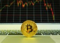 A gold bitcoin puts on a touch pad of a notebook computer with a stock graph in the background Royalty Free Stock Photo