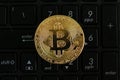 Golden bitcoin replica on a black numerical keyboard. Business and finance concept