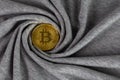 Golden bitcoin shiner on gray cotton cloth with swirl crumpling