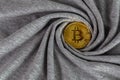 Golden bitcoin shiner on gray cotton cloth with swirl crumpling