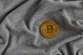 Golden bitcoin shiner on gray crumpled cotton cloth