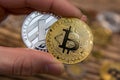 Golden Bitcoin and silver litecoin holding in mans fingers closeup Royalty Free Stock Photo