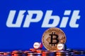 Golden bitcoin with two buy-sell cubes in a pile of coins on the background of the Upbit logo. The concept of buy-sell choice Royalty Free Stock Photo