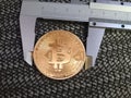 Golden Bitcoin and vernier caliper. Royalty Free Stock Photo