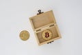 Golden bitcoin in wood box on a grey background.