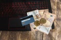 Golden bitcoins on euro banknotes and credit card on laptop keyboard suggesting bitcoin transaction or mining, wooden background