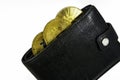 Golden bitcoins lie in black leather wallet closeup