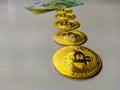 Golden bitcoins lined on the white background with paper money bill in the back showing the dominance and preference of