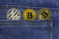 Golden bitcoins and silver litecoin lie back pocket of blue jeans closeup