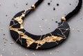 a golden and black necklace sitting on top of a gray surface