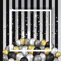 Golden black and silver balloons with white frame on shiny striated black and white surface