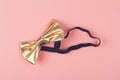 Golden bow tie on pink background