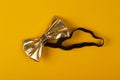 Golden bow tie on yellow background