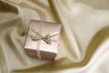 Golden box with ribbon on golden silk Royalty Free Stock Photo