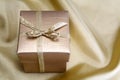 Golden box with ribbon on golden silk Royalty Free Stock Photo