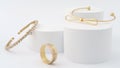 Golden bracelets and golden ring on white background. Modern design golden bracelets and ring on white platform Royalty Free Stock Photo