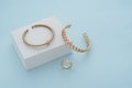 Golden bracelets and ring on white box on blue background with copy space Royalty Free Stock Photo