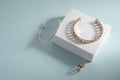 Golden bracelets and ring on white box on blue background Royalty Free Stock Photo