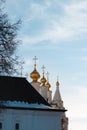 Golden brightly lit cupolas with orthodox crosses on top of a white stone church or cathedral are peeking from the dark stone old Royalty Free Stock Photo