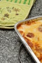 A golden brown lasagne displayed in a foil tin holder