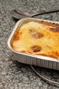 A golden brown lasagne displayed in a foil tin holder