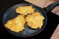 Golden-brown potato pancakes frying in a speckled non-stick pan on a hob Royalty Free Stock Photo