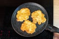 Golden-brown potato pancakes frying in a speckled non-stick pan on a hob Royalty Free Stock Photo